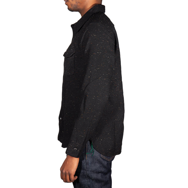 Person wearing a black speckled shirt on a white background