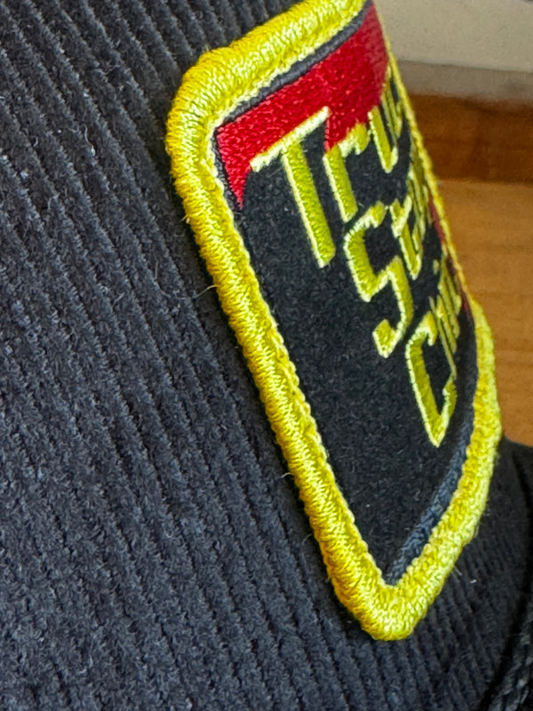 Embroidered patch with text and symbols on a dark fabric background