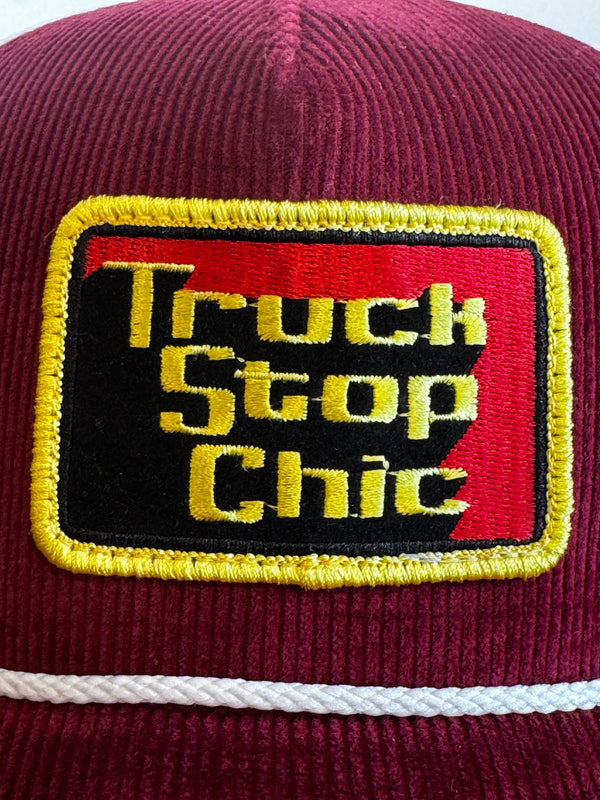 Close-up of a maroon bag with a yellow and red logo featuring text.