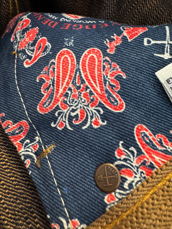Close-up of a blue fabric pouch with red and white patterns on a textured surface.