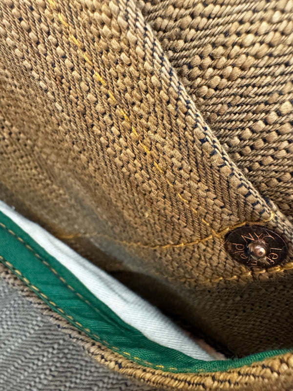 Close-up of a button on a brown fabric garment with visible stitching.