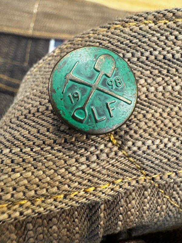 Green button with engraved text on a textured fabric background