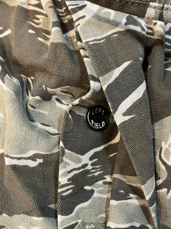 Camouflage-patterned shirt with a 'Left Field' button on a close-up of fabric texture.