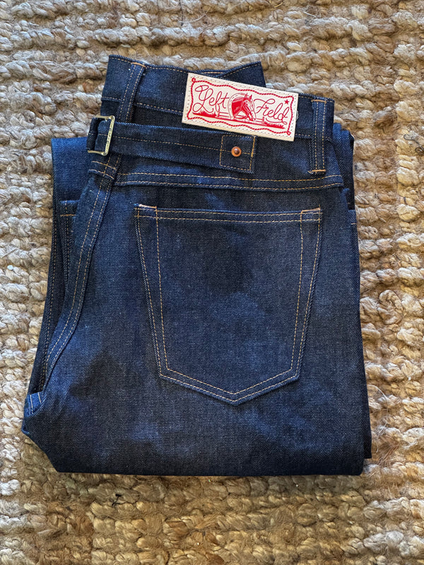 Folded pair of blue jeans with a tag on a textured beige surface