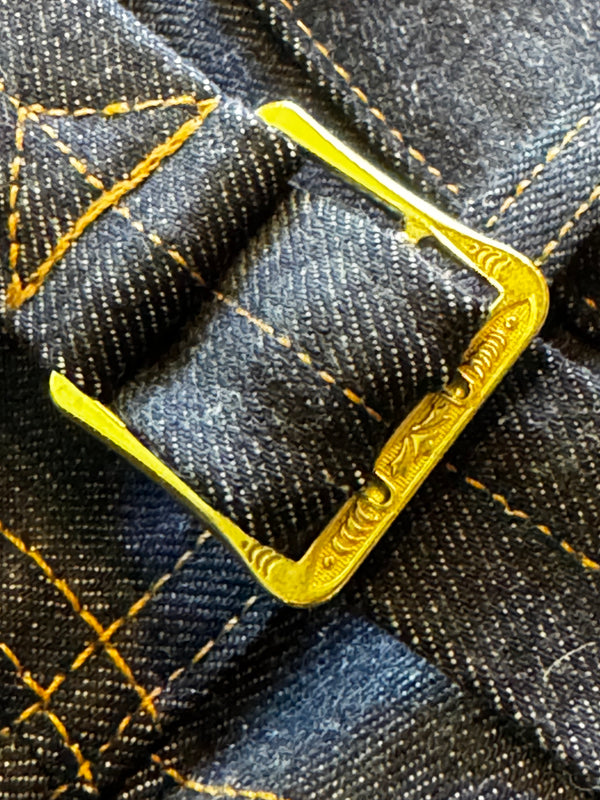Gold metal buckle on a denim fabric background