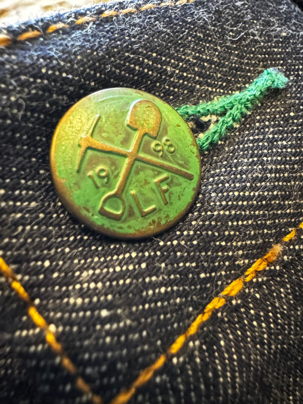Green button with a logo on a denim fabric background
