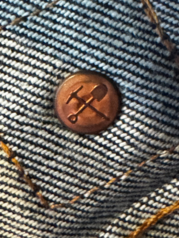 Close-up of a button on denim fabric with a logo.