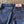 Close-up of a pair of blue jeans with a LF label on a textured surface.