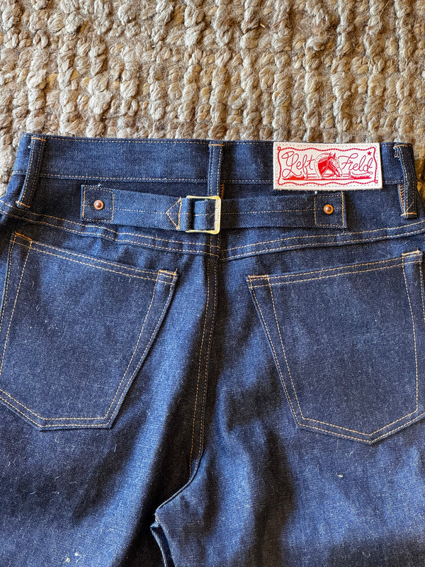 Close-up of a pair of blue jeans with a LF label on a textured surface.