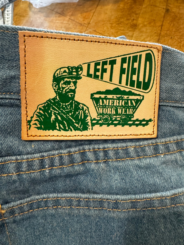 Close-up of a denim jacket with a 'LEFT FIELD' patch featuring a graphic design.