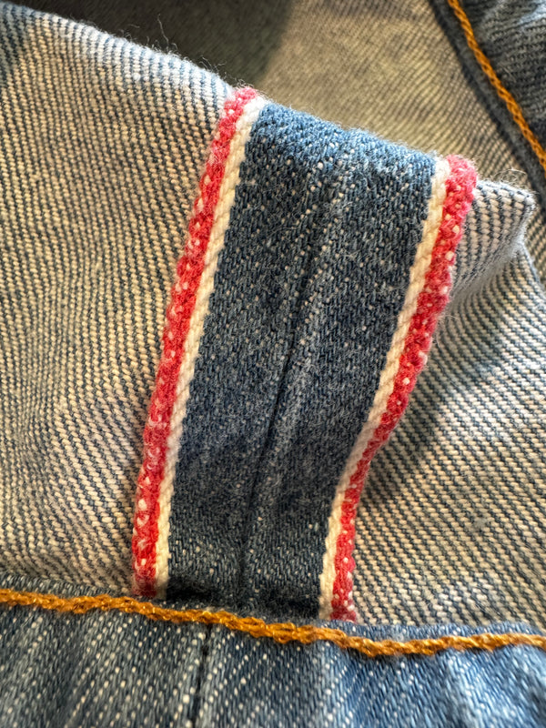 Close-up of denim fabric with red and white stitching