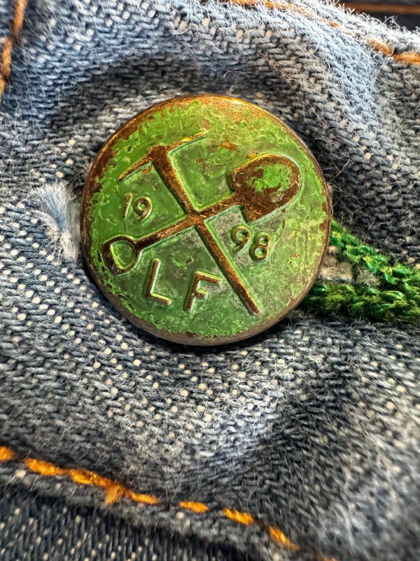 Rustic metal button with green patina on denim fabric