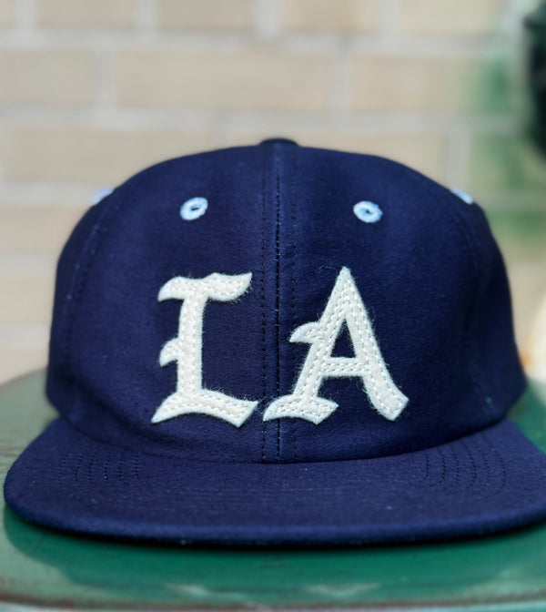 Navy blue cap with 'LA' logo on a green surface