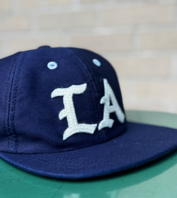 Navy blue cap with 'LA' logo on a blurred background