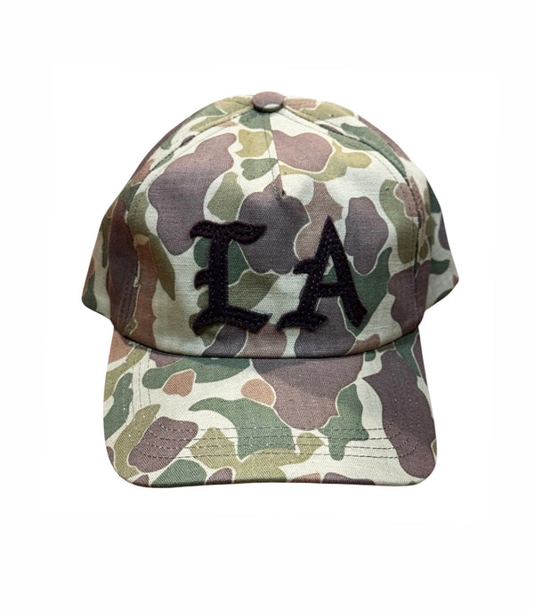A baseball cap with a green, brown, and beige camouflage pattern, featuring black embroidered letters 'LA' on the front, set against a plain white background.