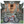 A custom chopper motorcycle with a red body and chrome details is parked in front of an ornate Balinese temple with carved stone statues and a red-and-gold door.