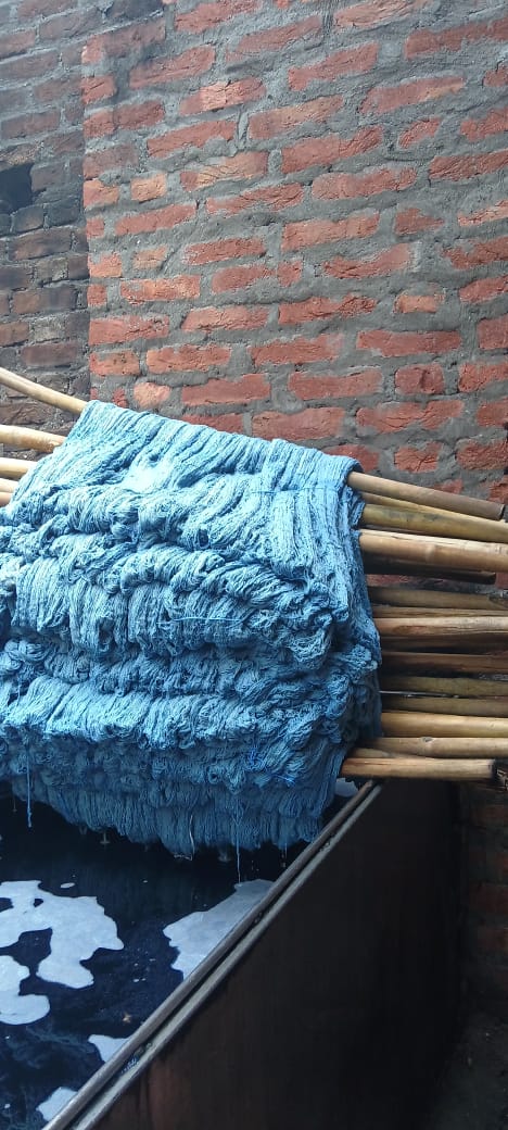 Blue textured fabric draped over a bamboo structure against a brick wall.