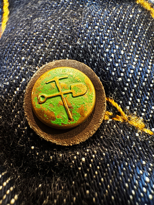 Rustic metal button with green patina on denim fabric
