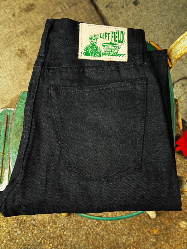Folded black pants with a 'Left Field' label on a textured surface