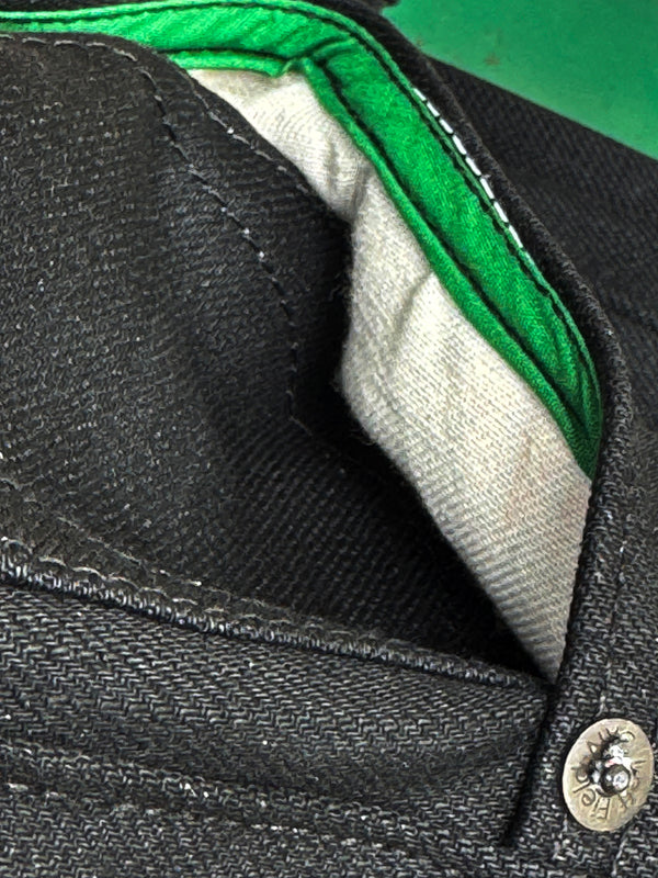 Close-up of a black jacket with green lining and button detail.