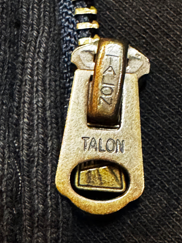 Close-up of a Talon zipper pull on a black fabric background