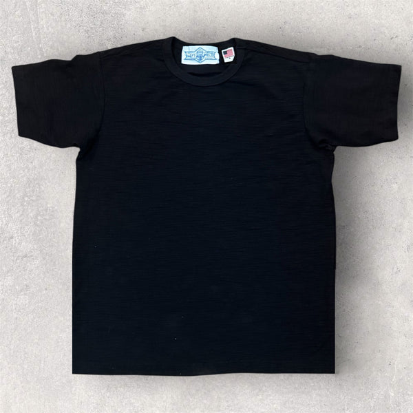 Black t-shirt with a brand label on a light gray background