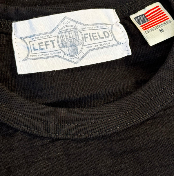 Close-up of a black shirt with 'Left Field' label and American flag patch.