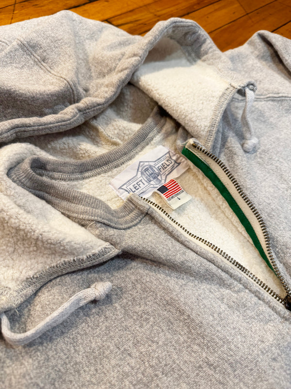 Gray fleece jacket with a brand label on a wooden floor