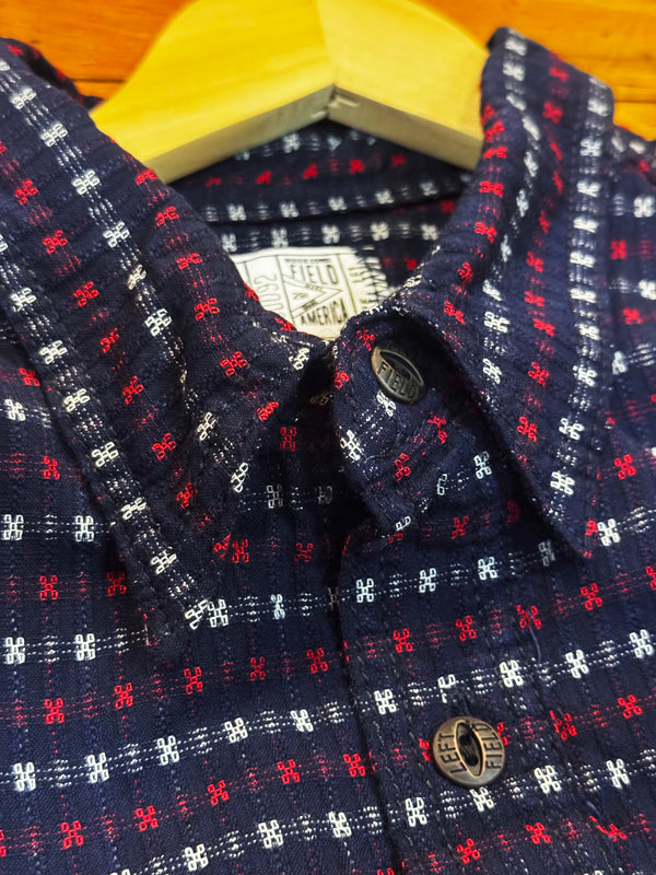 Navy blue shirt with red and white pattern on a wooden surface