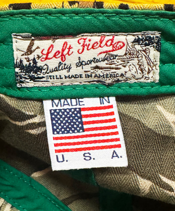 Close-up of a camouflage garment showing the inner neck label with 'Left Field Quality Sportswear' and a separate white 'MADE IN U.S.