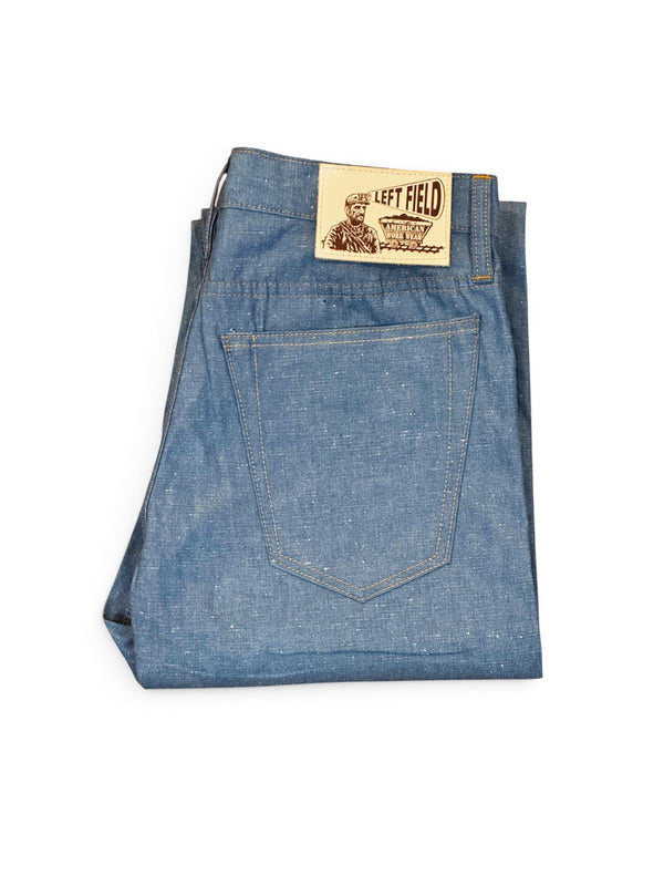 A pair of folded blue denim jeans with a tan leather brand patch on the back waistband, photographed on a clean white background.