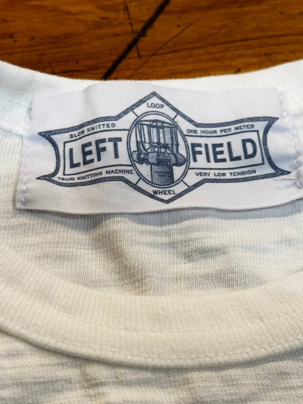 Label on a white shirt with 'LEFT FIELD' branding on a wooden surface