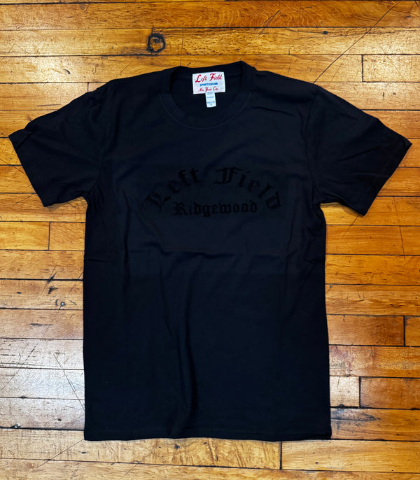 Black t-shirt with text on a wooden floor