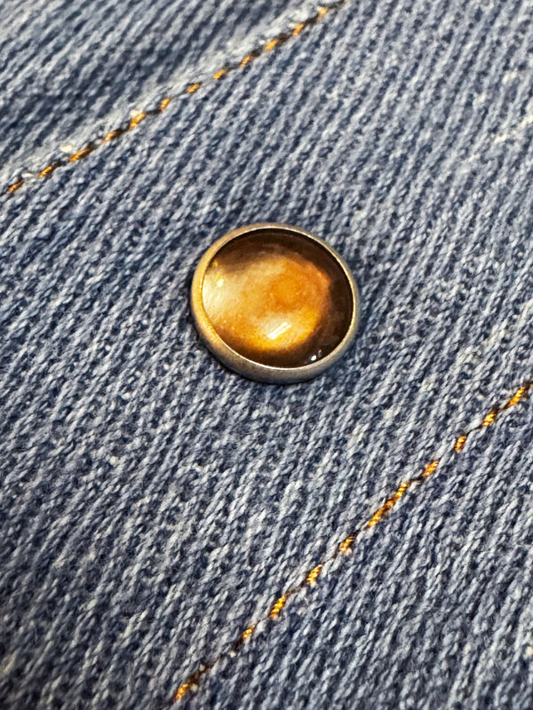 Close-up of a gold button on blue denim fabric