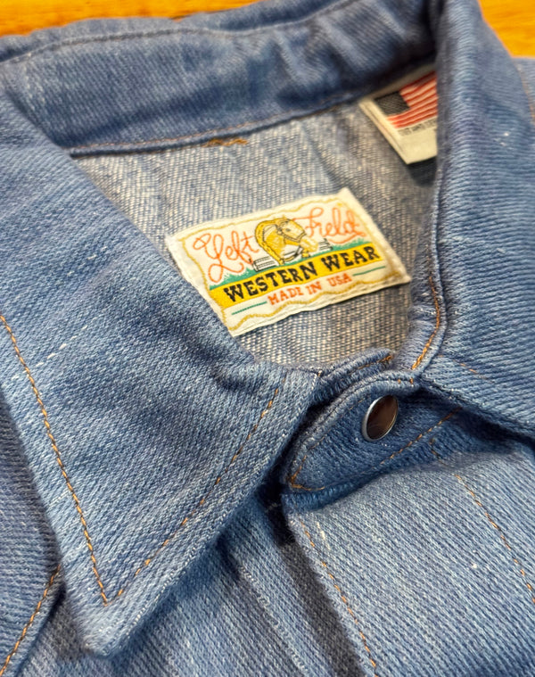 Close-up of a denim jacket with a label on a wooden surface