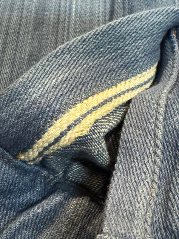 Close-up of blue denim fabric with a yellow stitching detail
