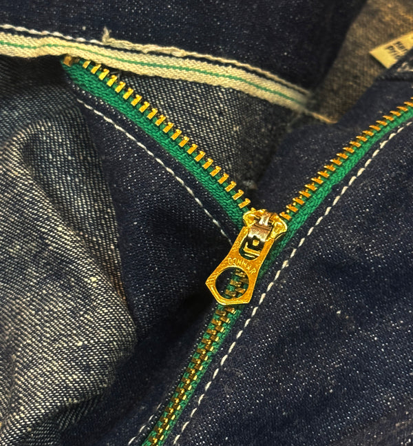 Close-up of a gold zipper on dark denim fabric