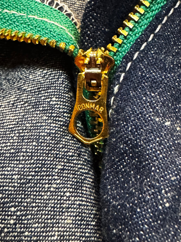 Close-up of a gold zipper on denim fabric with 'Connar' branding.